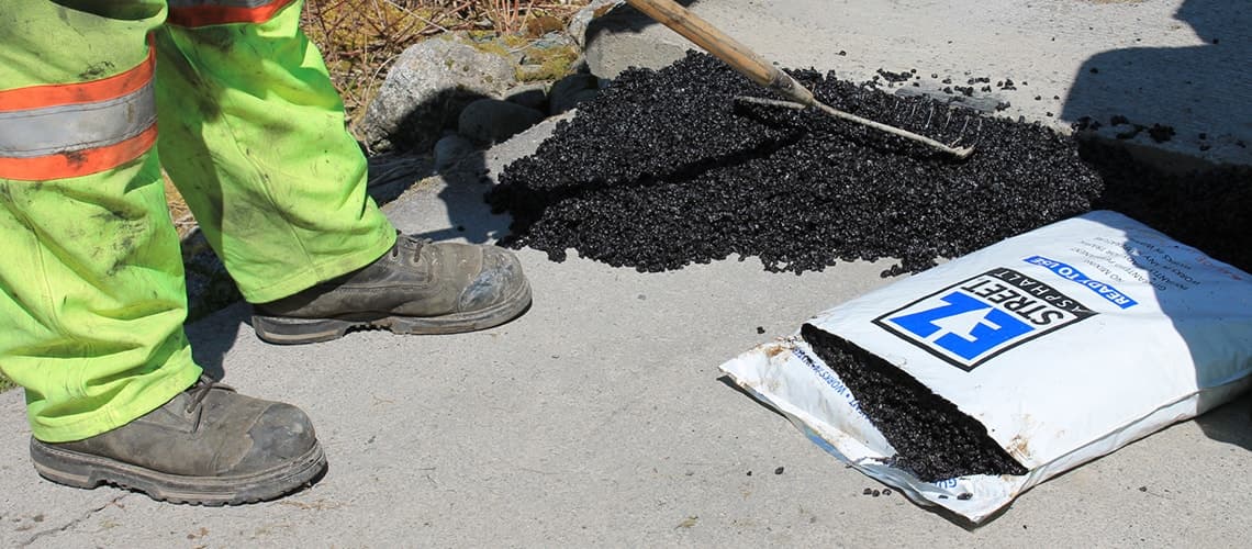 Worker pouring EZ Street into pothole on golf course
